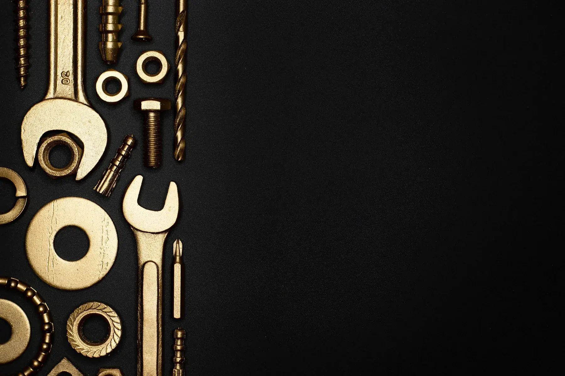 Brass and gold tools laid out on a black bench.