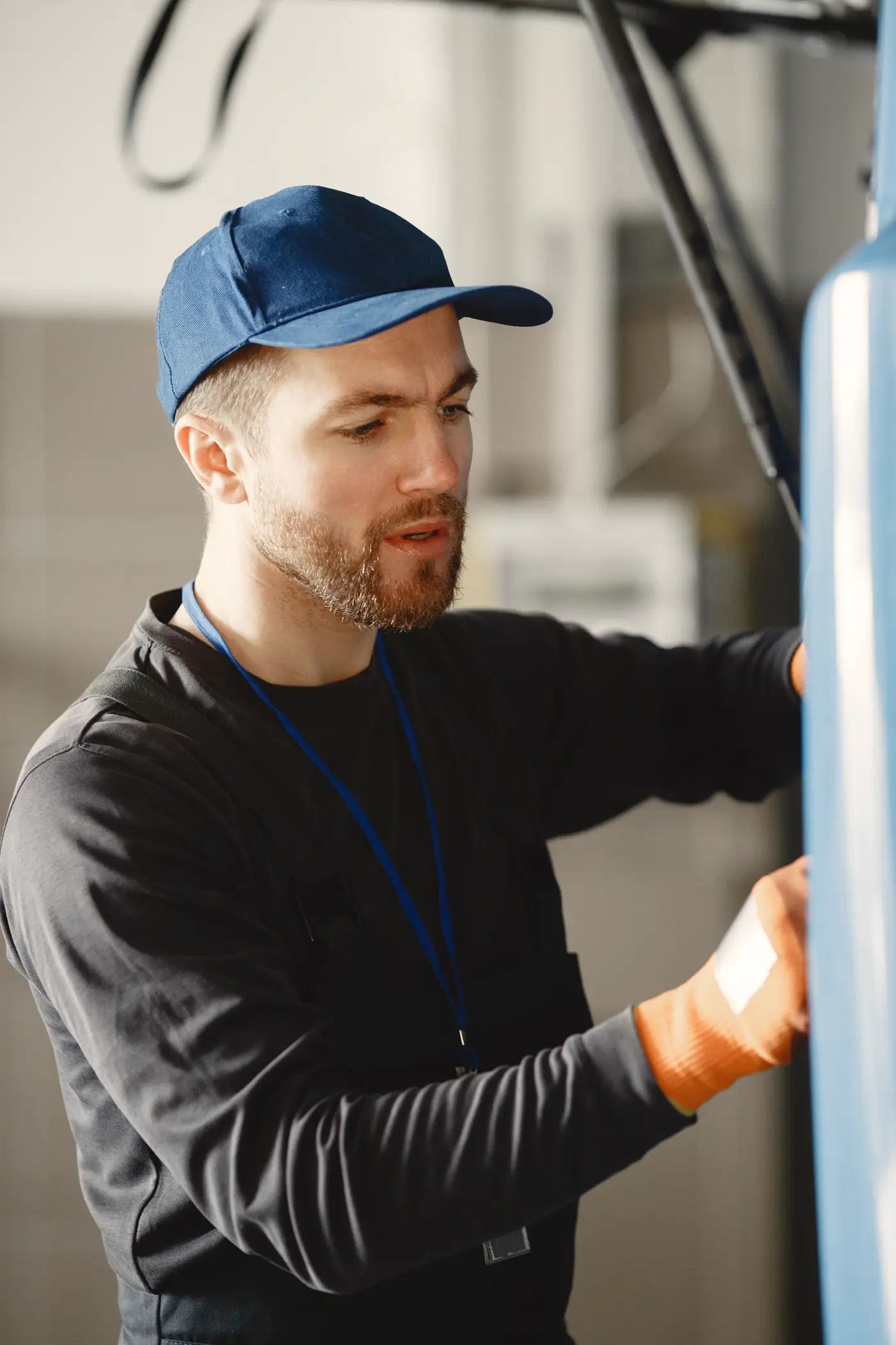 A technician in a work cap, focused on the equipment in front of him.